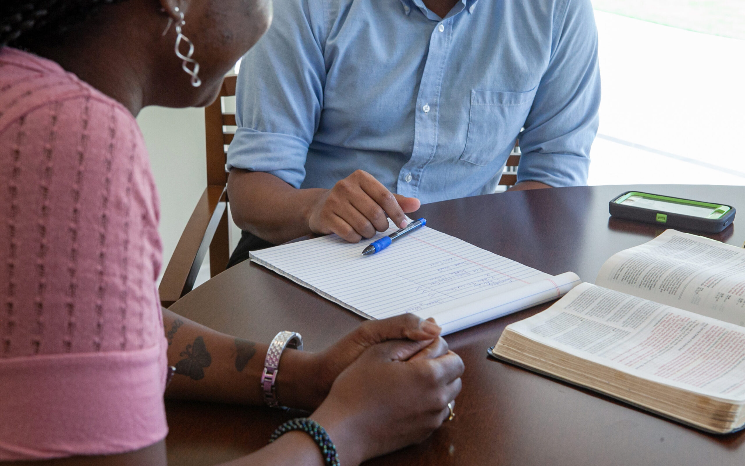 image of people sitting at a table with a notebook